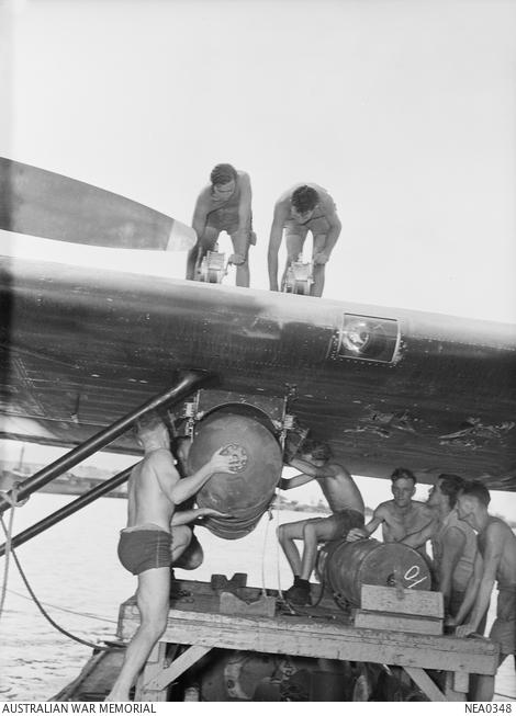 RAAF armourers hoist a magnetic mine into place under the wing of a Consolidated PBY Catalina flying boat.