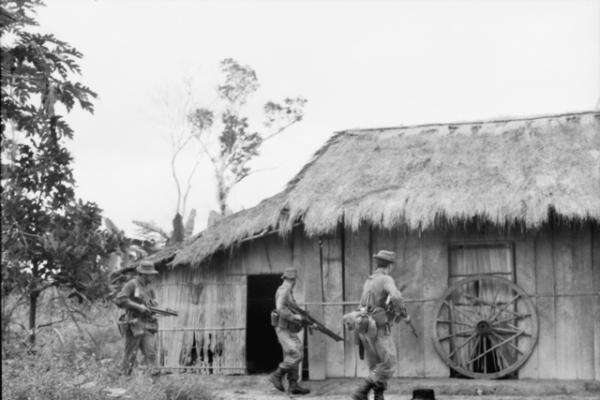 Troops of C Company, 1RAR, closing in on a known Viet Cong house, 1965