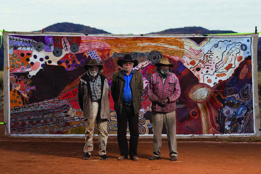 Artists from the APY Art Centre Collective, Ginger Wikilyiri, Frank Young, and Keith Stevens with Kulatangku angakanyini manta munu Tjukurpa (Country and Culture will be protected by spears).