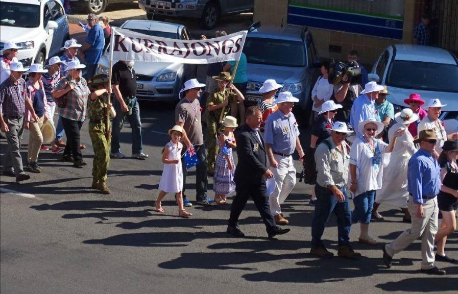 Descendents of Kurrajongs wearing white hats at they march.
